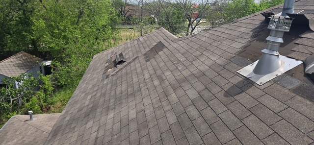 Wind damage on a Taylor-area roof: a torn, missing section near a roof vent, seen from above