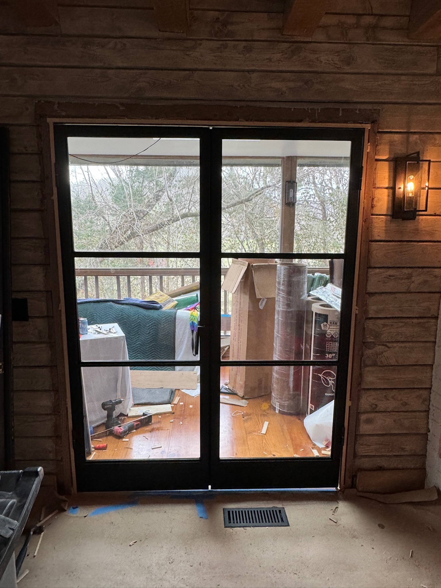 Black steel-framed glass double doors opening onto a deck