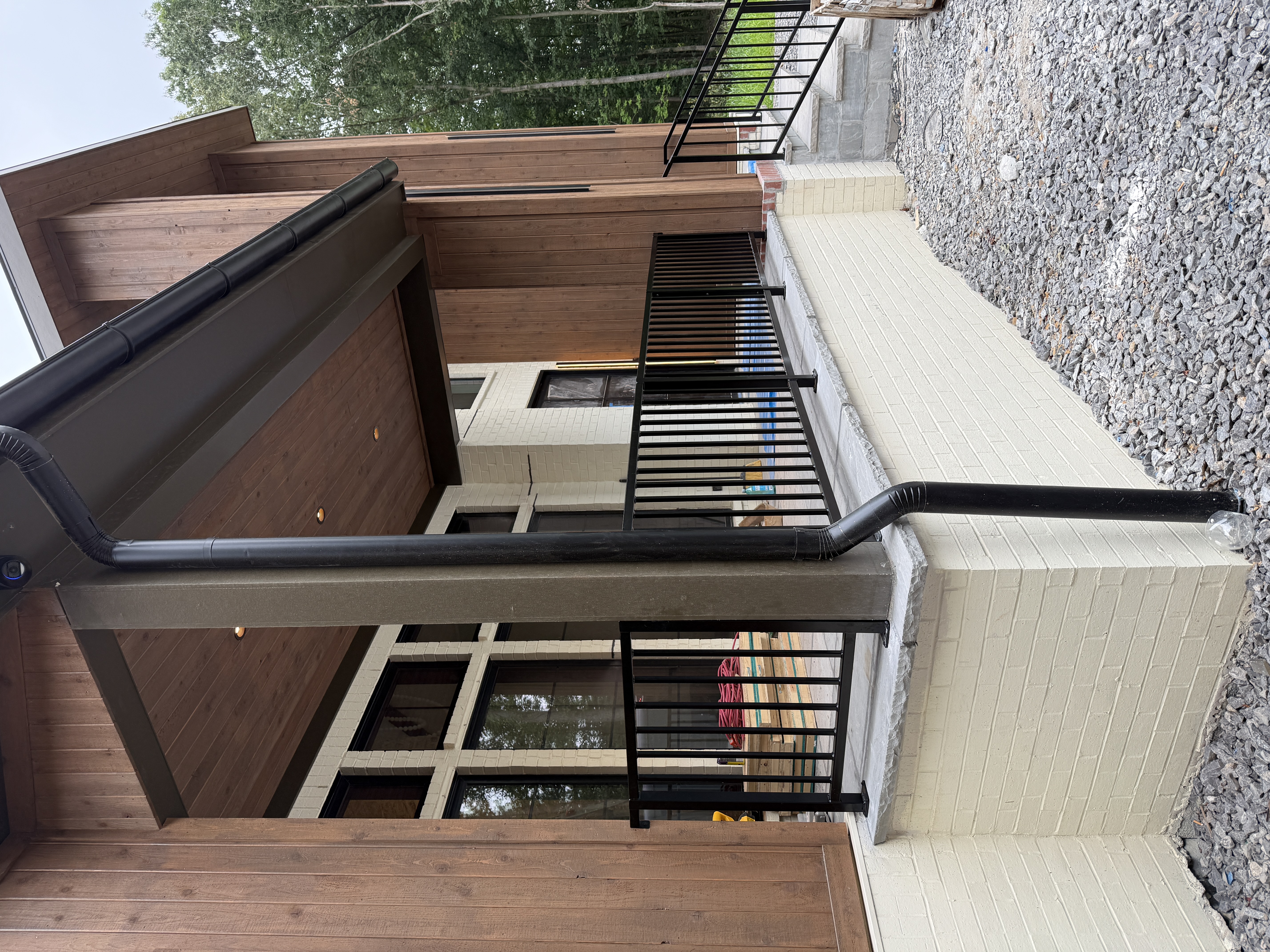 Black steel balcony railing on a brick-and-wood exterior
