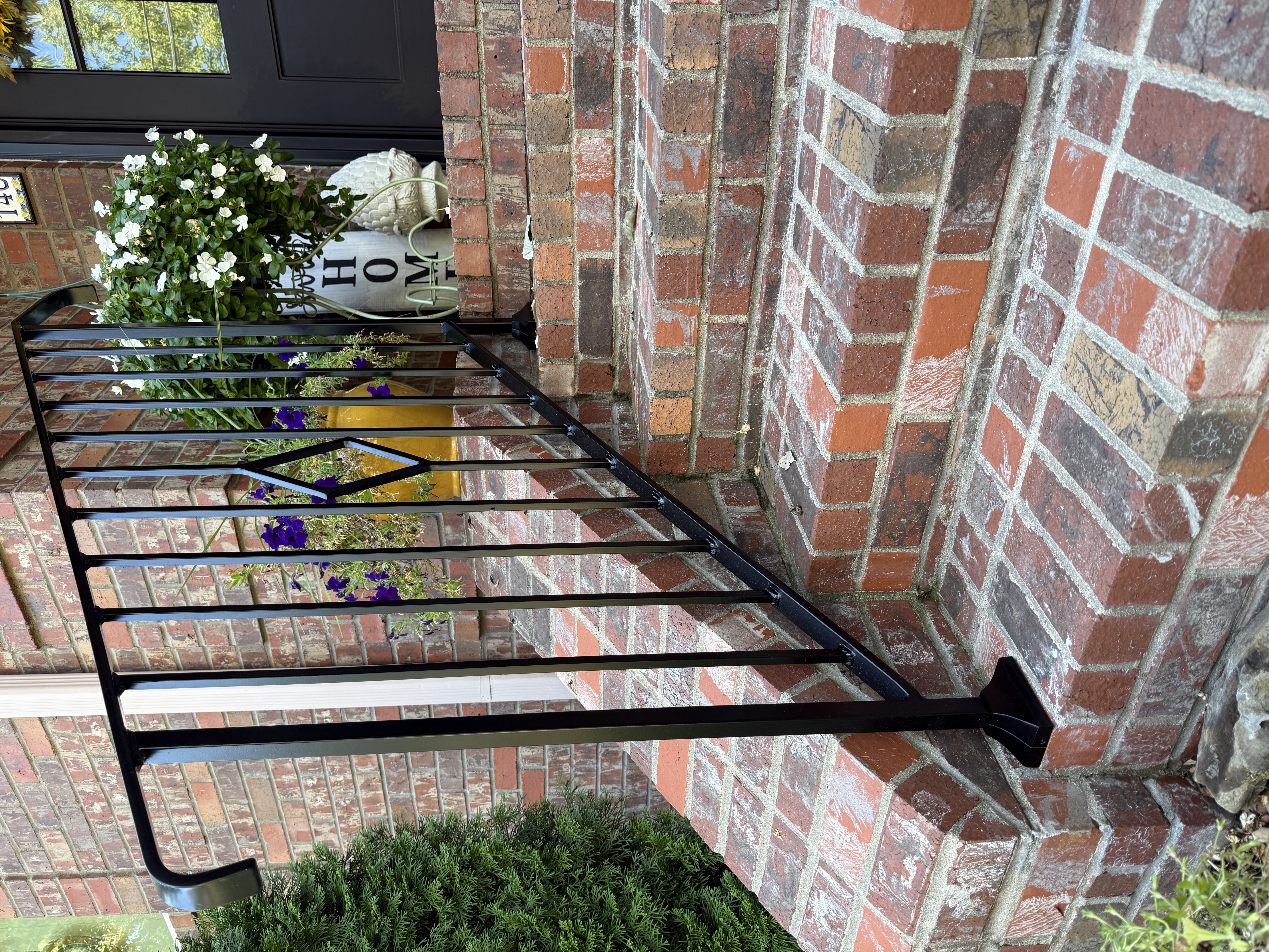 Finished exterior black steel handrail on brick steps with planters