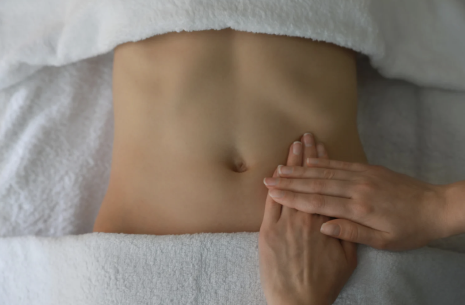 Gentle lymphatic drainage massage on the abdomen in a calm therapeutic setting