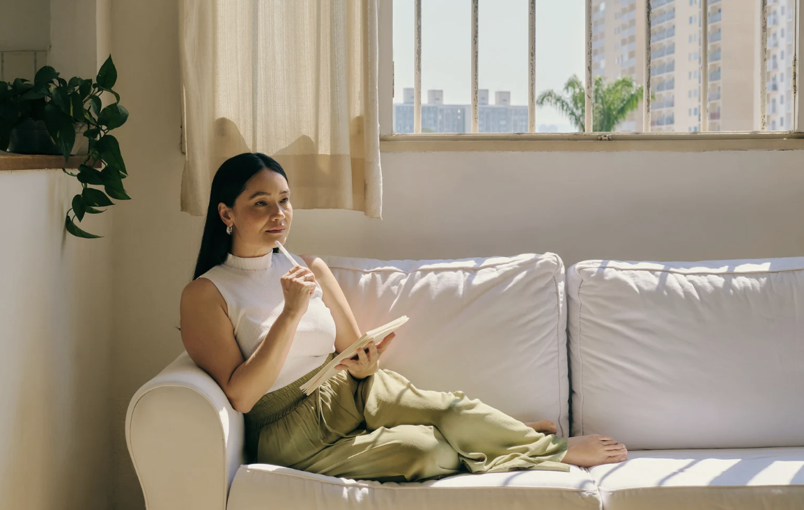 A woman sitting with a notebook, reflecting
