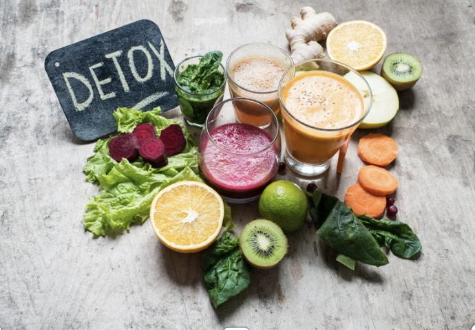 A vibrant spread of fresh fruits, vegetables, and juices with a chalkboard reading DETOX