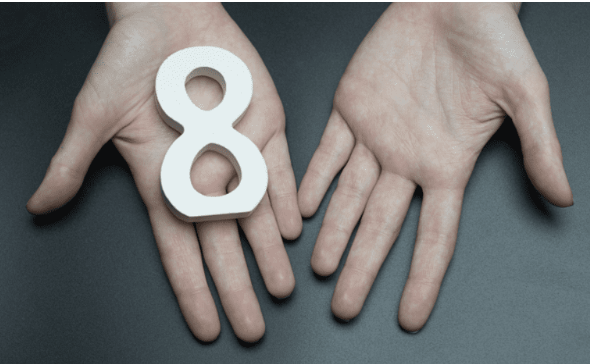 Two open hands cupping a wooden figure-eight, the infinity symbol turned upright