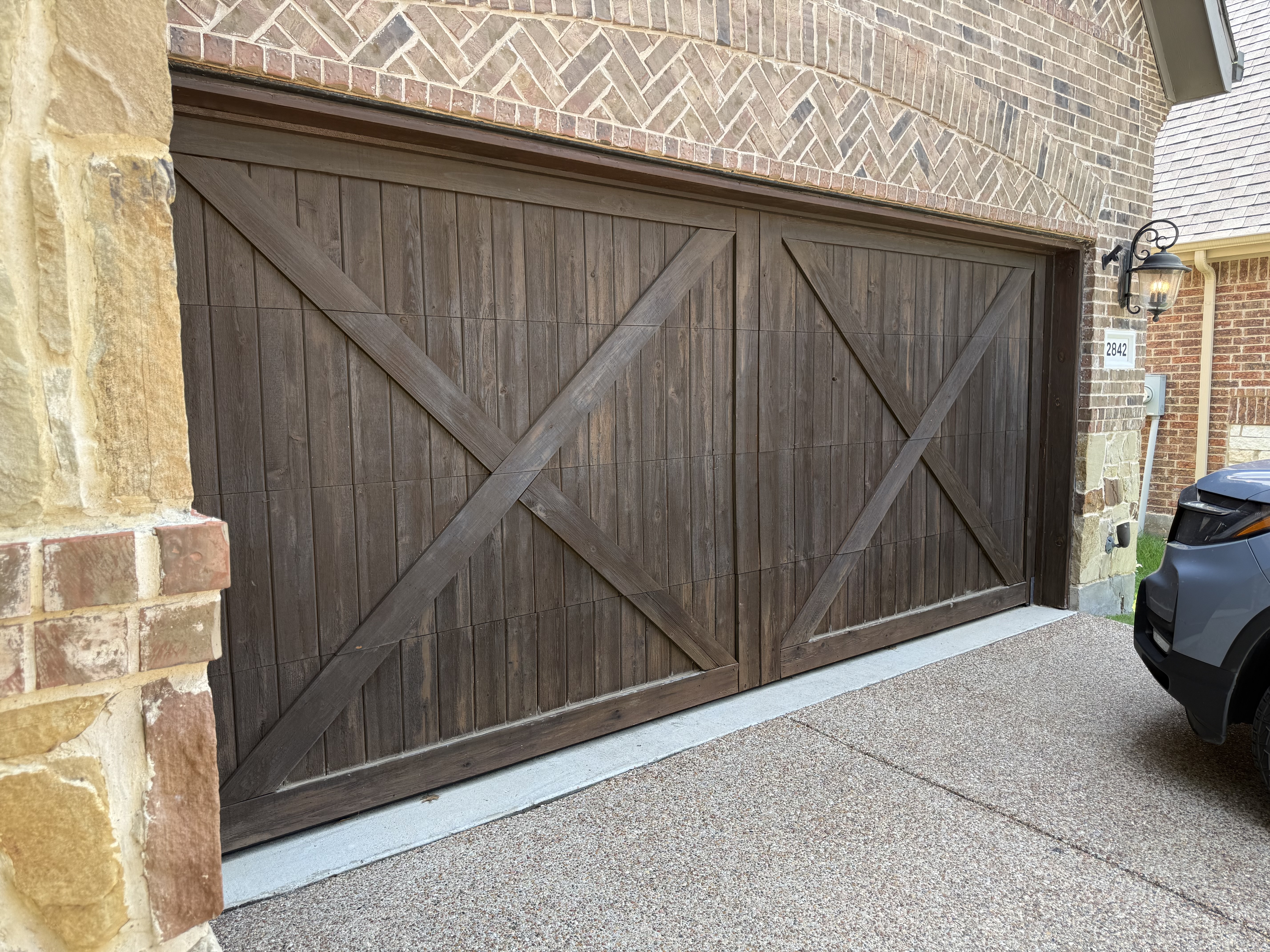 The same garage door finished in a rich, even stain with clean carriage-style panels